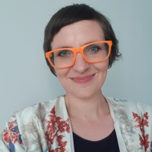Headshot of woman with big bright orange glasses